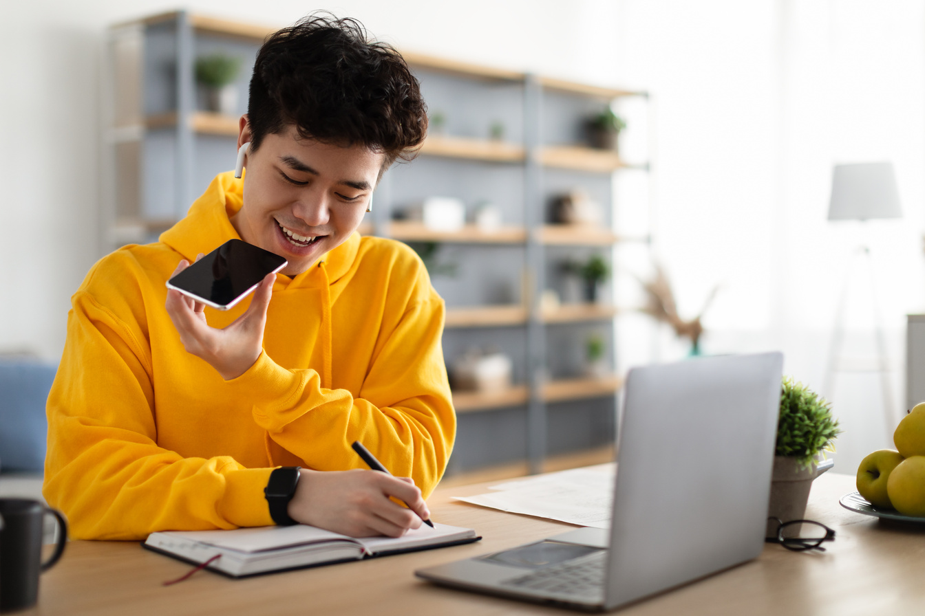 Asian guy using voice assistant on cellphone